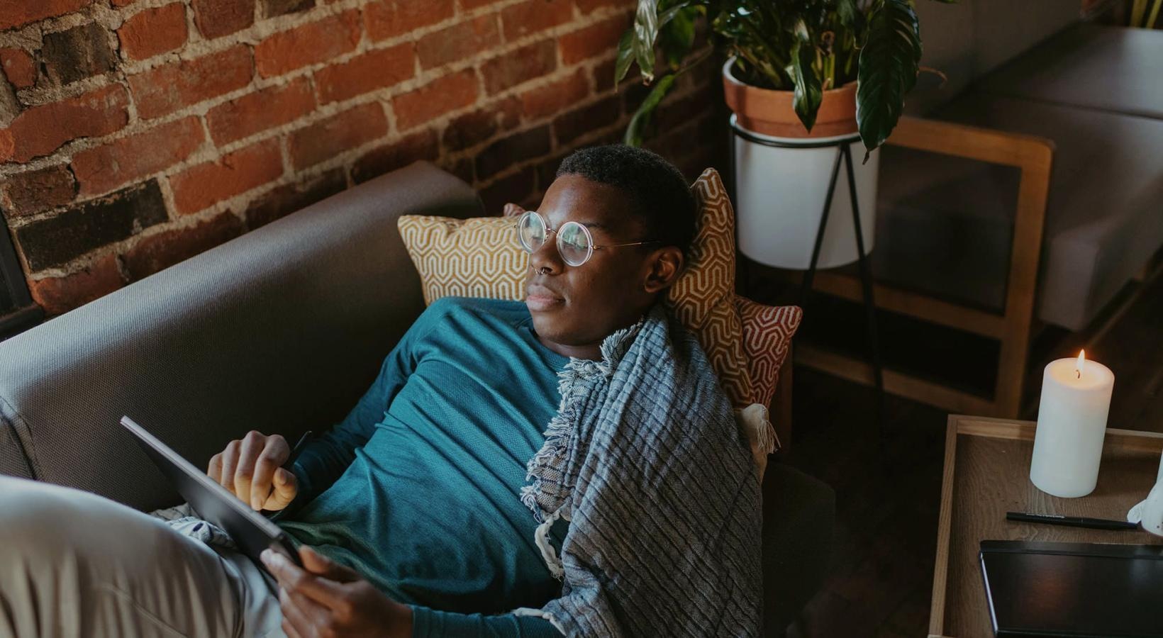 Relax and unwind in stylish living spaces a man looks at his tablet while lying on his living room couch
